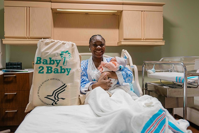 A new mother with her baby receiving a Newborn Supply Kit at a hospital