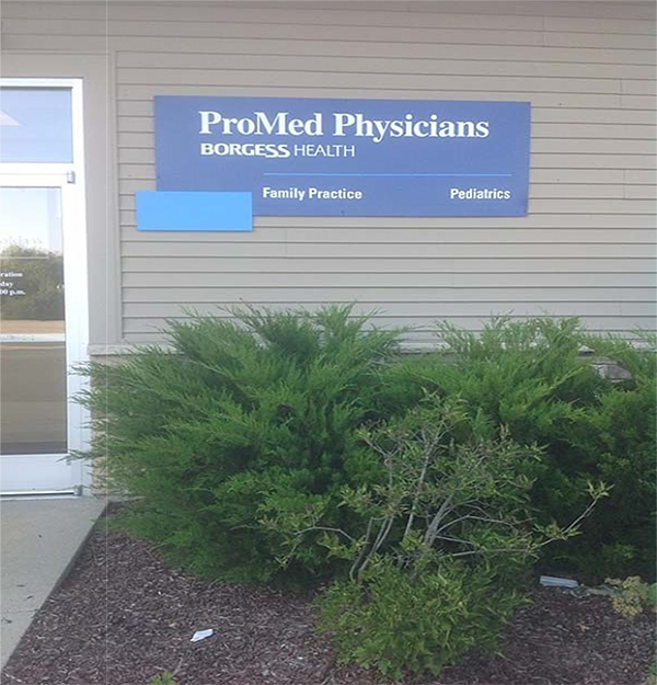 A blue sign on the side of a beige building next to a doorway. White text: 1st line, ProMed Physicians (large text); 2nd line, BORGESS HEALTH (smaller text) and 3rd line, Family Practice Pediatrics (even smaller text).