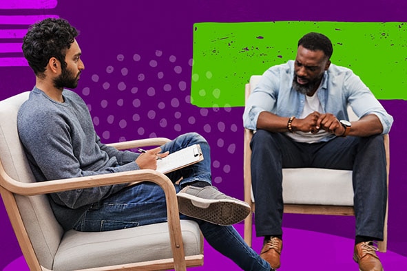 A young male therapist writing notes on a clipboard as a young man talks next to him.