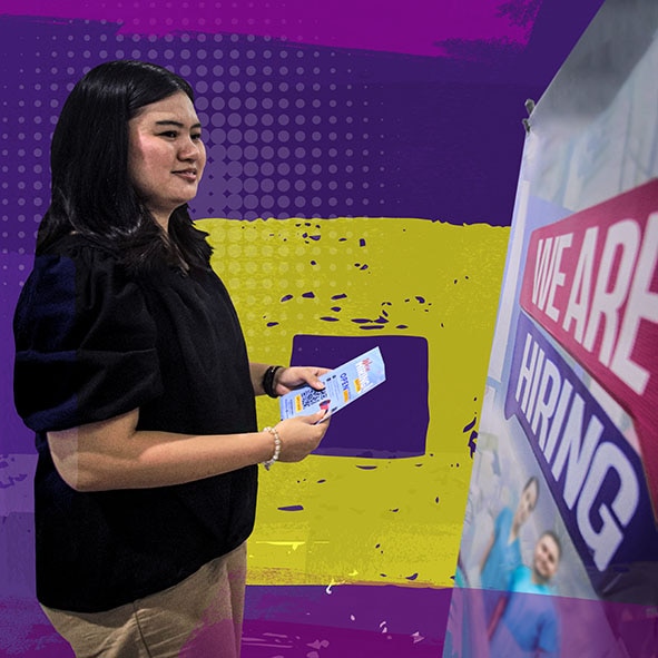 A young woman looking at a poster that says We Are Hiring