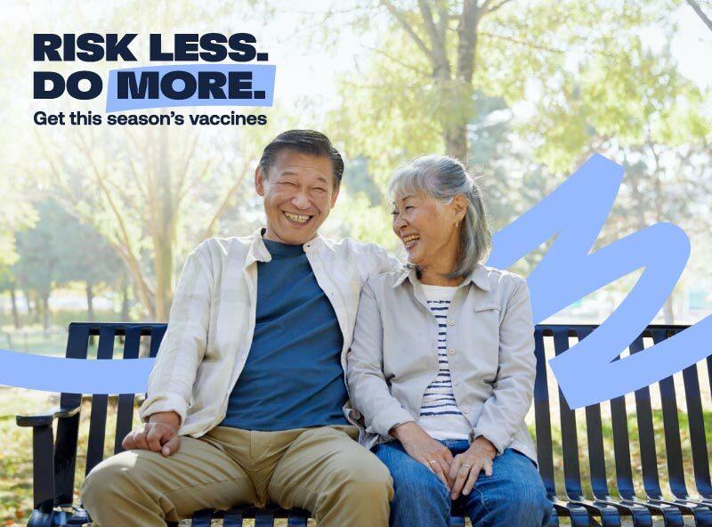 An older couple smiles on a park bench outdoors. The text reads: "RISK LESS. DO MORE. Get this season's vaccines