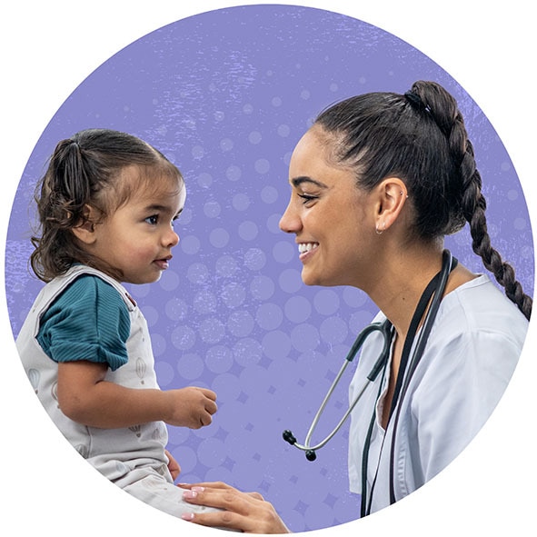 Female toddler looking at a young female doctor smiling back at the toddler